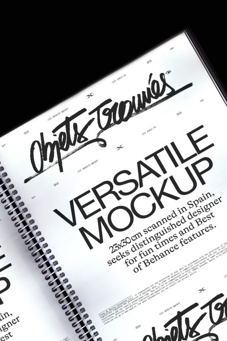 Angled view of spiral notebook with white pages showing large typography layout