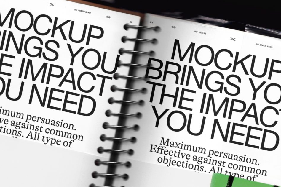 Open spiral notebook pages showing bold sans serif typography with body text, shot at an angle