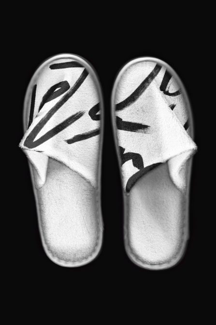 Pair of white slides with black slash graphic design on both soles