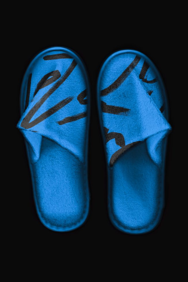 Blue plush slippers with abstract pattern isolated on black background, high-resolution mockup for footwear design presentation.