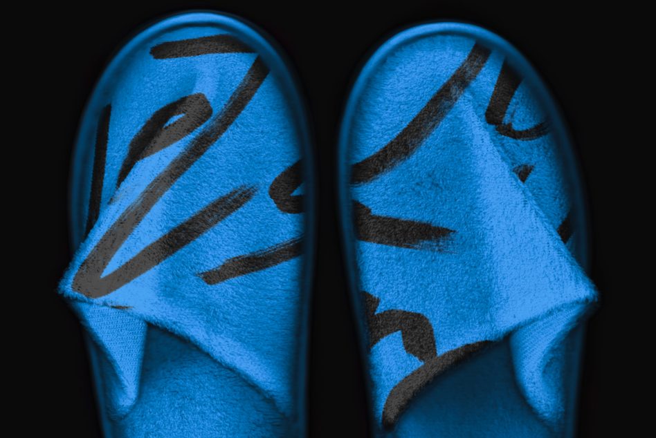 Pair of blue slippers with black slash graphic design overhead view