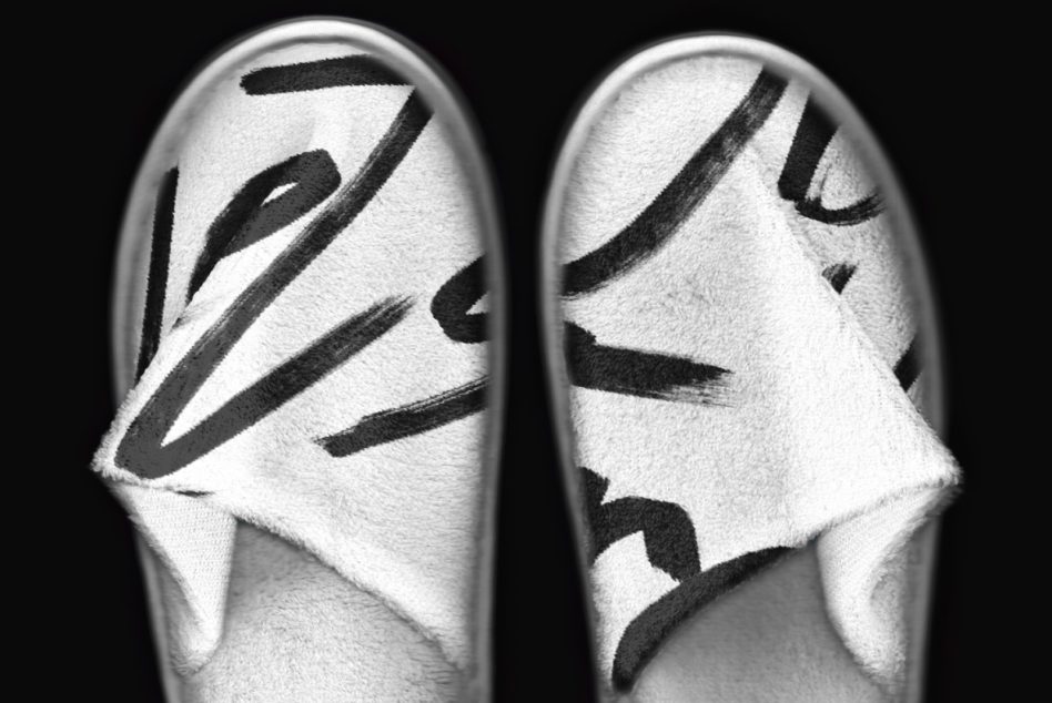 Pair of white slippers with black slash graphic design overhead view