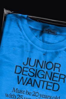 Bright blue t-shirt with black bold typography about junior designer role