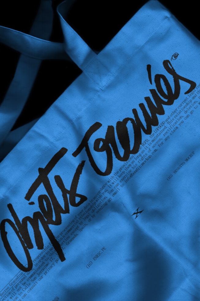 Blue tote bag with unique black handwritten font design, showcasing custom typography for graphic design and branding assets.