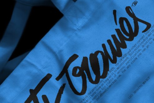 Close-up view of a textured fabric with handwritten style font, showcasing script typography, suitable for graphic design, font display, or texture mockup.