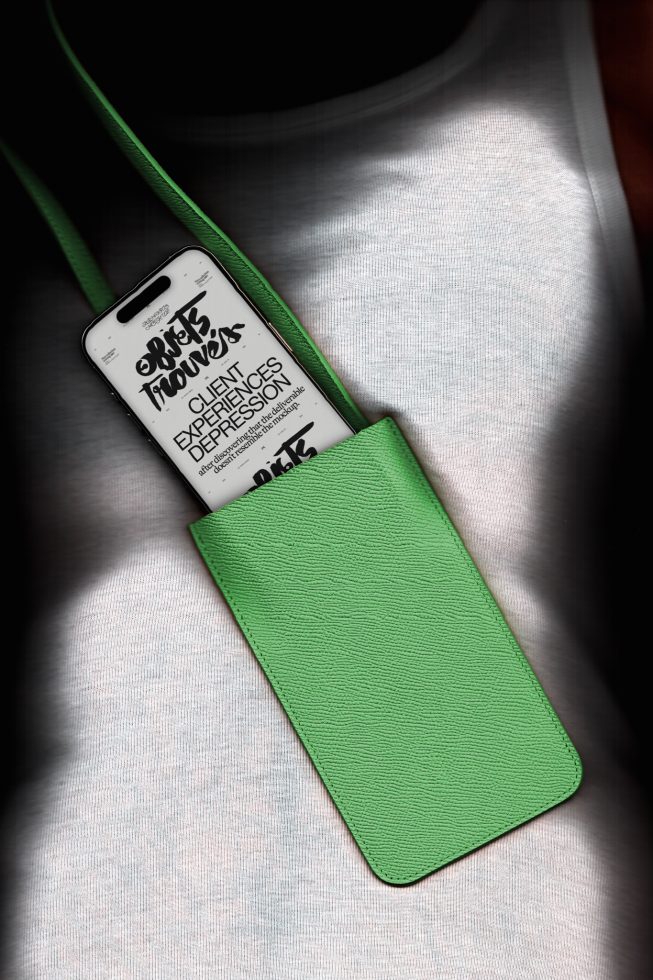 Smartphone in a green leather case mockup with a script font display, positioned in a pocket, ideal for designers' presentations.