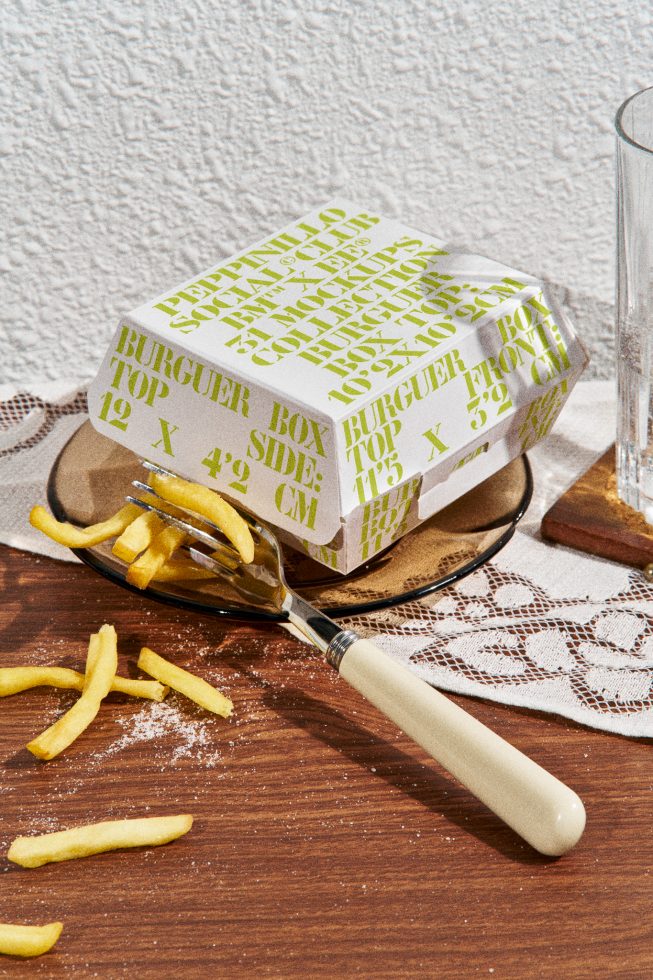 Fast food packaging mockup with styled burger box and scattered fries on wooden surface ideal for restaurant branding design.