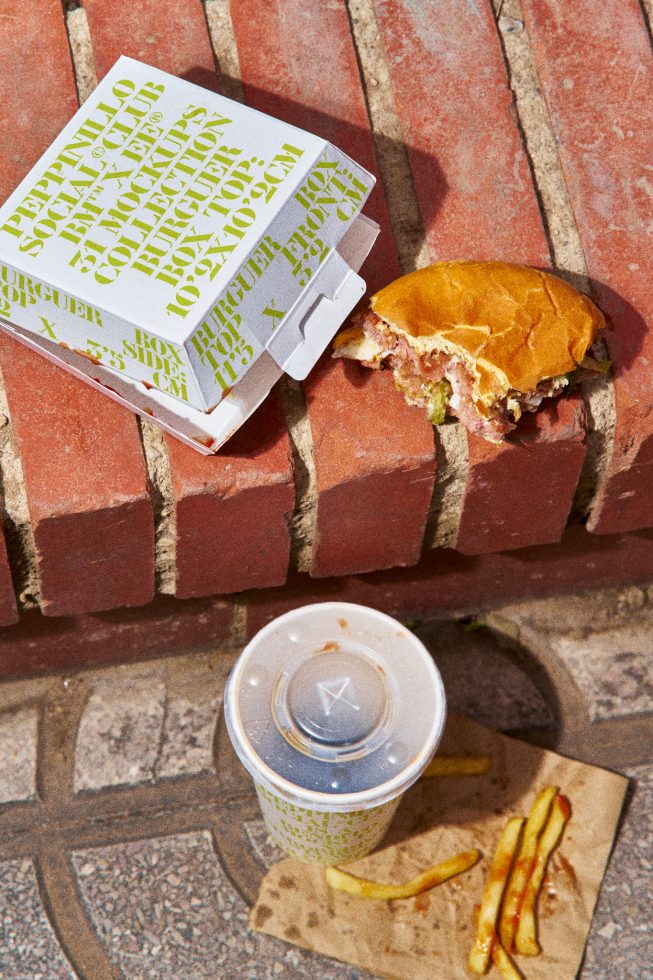 Fast food packaging design mockup featuring a burger box, drink cup, and fries on a brick surface with dynamic shadow play. Ideal for branding visuals.