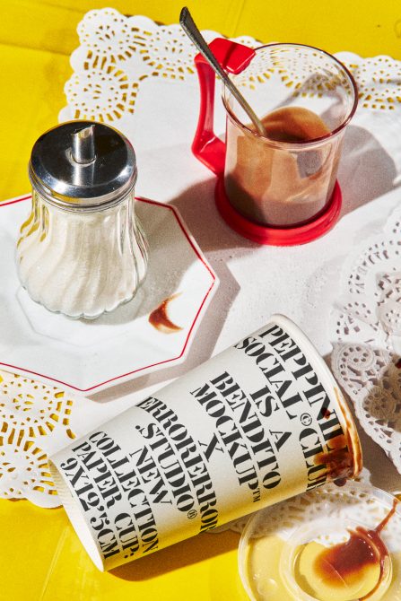 Vintage diner setting with sugar dispenser and stained newspaper graphic mockup, sunlit retro vibe, great for presentation templates.