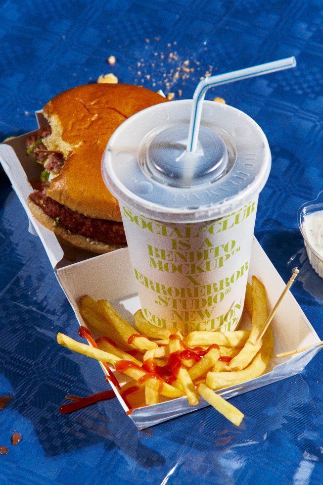 Realistic food mockup with a half-eaten burger, fries with ketchup, and a soda cup on a blue background. Ideal for presentation and advertising.