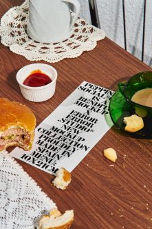 Flat mockup card in black text on wood table with burger crumbs, jam cup, cookies