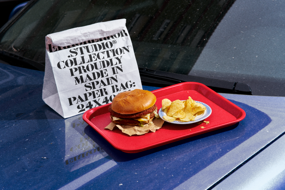 High-resolution image of a fast food meal with a burger and chips on a car hood for mockup designs, showcasing packaging and branding.