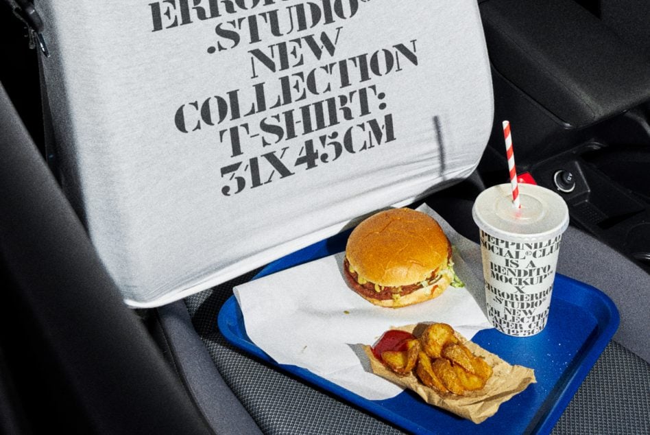 Light shirt detail in car with burger, fries, cup on blue tray, dark serif text overlay