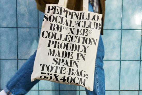 Person holding a tote bag with bold typography design against a blue tile background, emphasizing fonts and mockups for creative projects.
