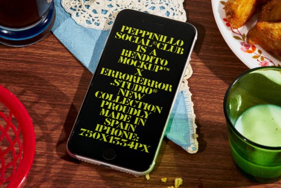 ALT: Smartphone screen mockup design displaying bold text, surrounded by beverages and snacks on a wooden surface, ideal for graphic designers.