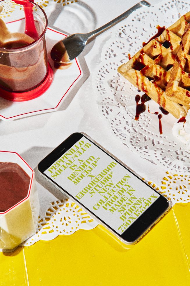 Smartphone screen mockup on yellow table with dessert, showcasing font design with stylized text, ideal for graphic presentations.