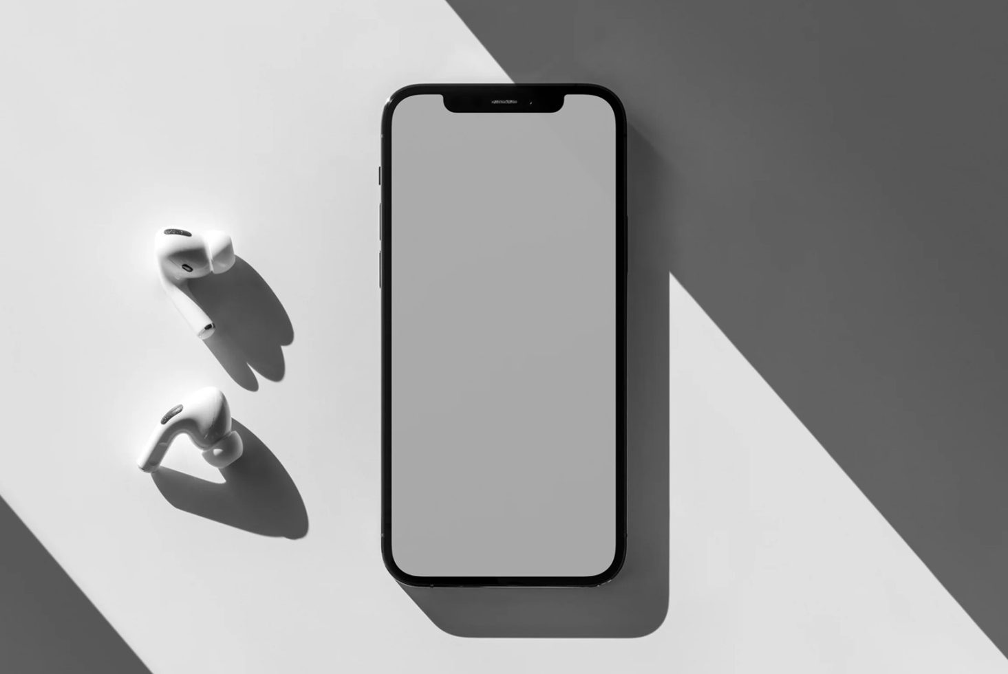 Minimalist smartphone mockup with wireless earbuds on a white surface with shadow play, ideal for app design presentation.