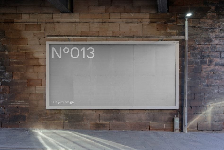 White-framed billboard with N°013 mounted on red brick warehouse wall