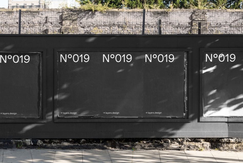 Row of black storefront windows displaying N°019 with tree shadows cast across