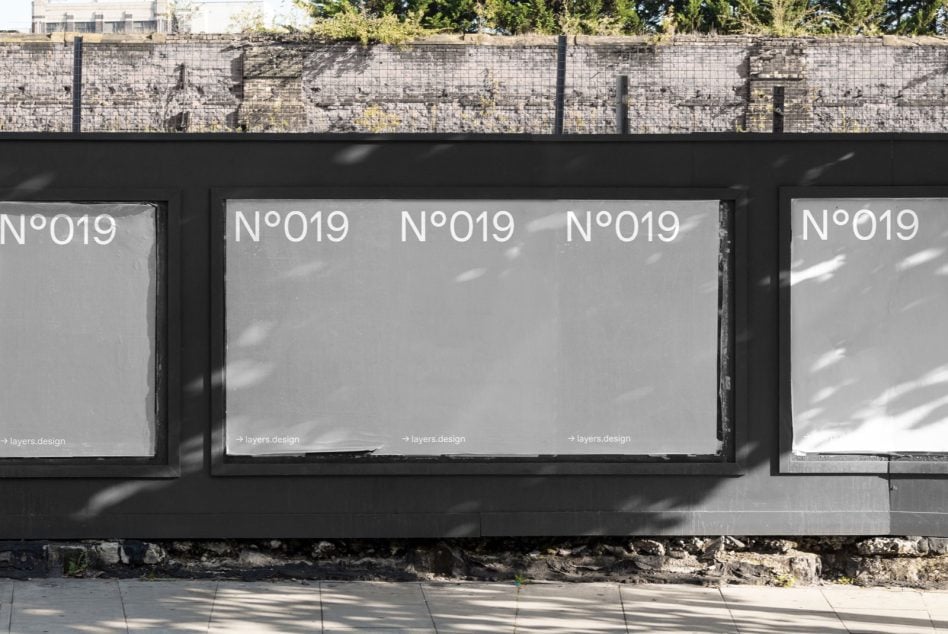 Multiple storefront windows with black frames showing N°019 in bright sunlight