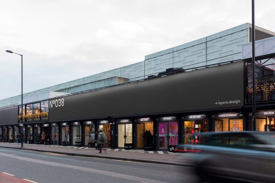 Street-level retail storefront billboard N°038 with shops below at dusk with dark surface