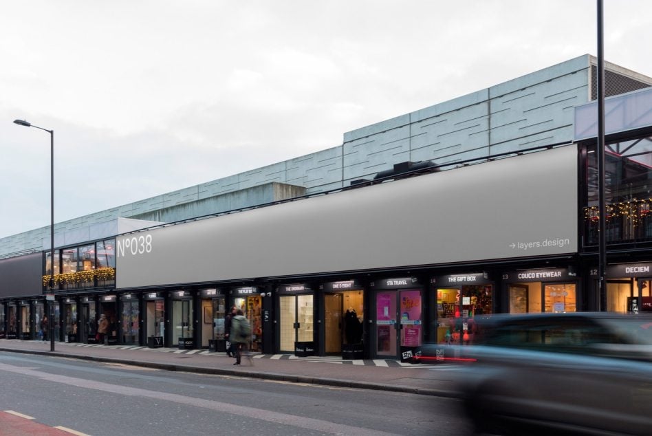 Street-level retail storefront billboard N°038 with shops below during daylight
