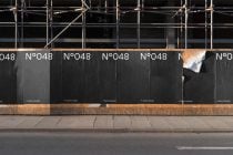 Repeating N°048 pattern across construction hoarding on city street