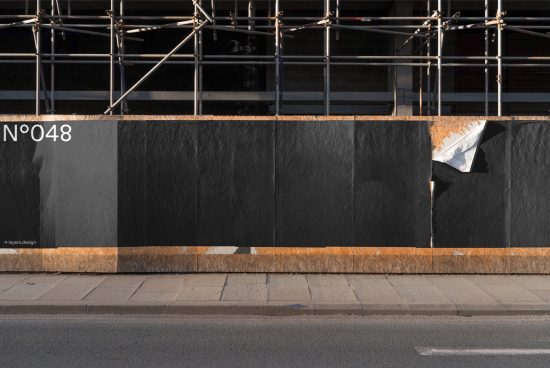 Urban mockup of torn black posters on exterior wall with scaffolding, for designers to display their work.