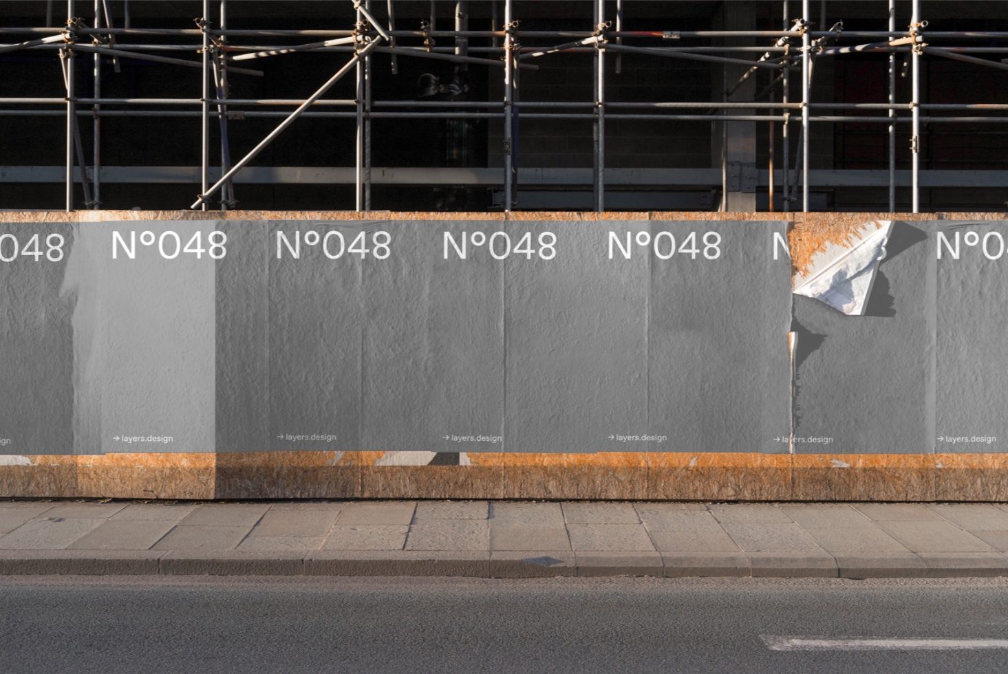 Urban poster mockup on a sunlit wall with scaffolding for designers, showcasing realistic textures and street environment.