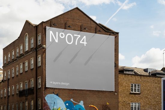 Urban billboard mockup on a brick building exterior under a blue sky, showcasing empty advertisement space for designers.