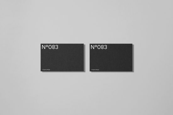 Two black minimalist business card mockups on a clean gray background, demonstrating simple yet elegant design layouts for presentation.