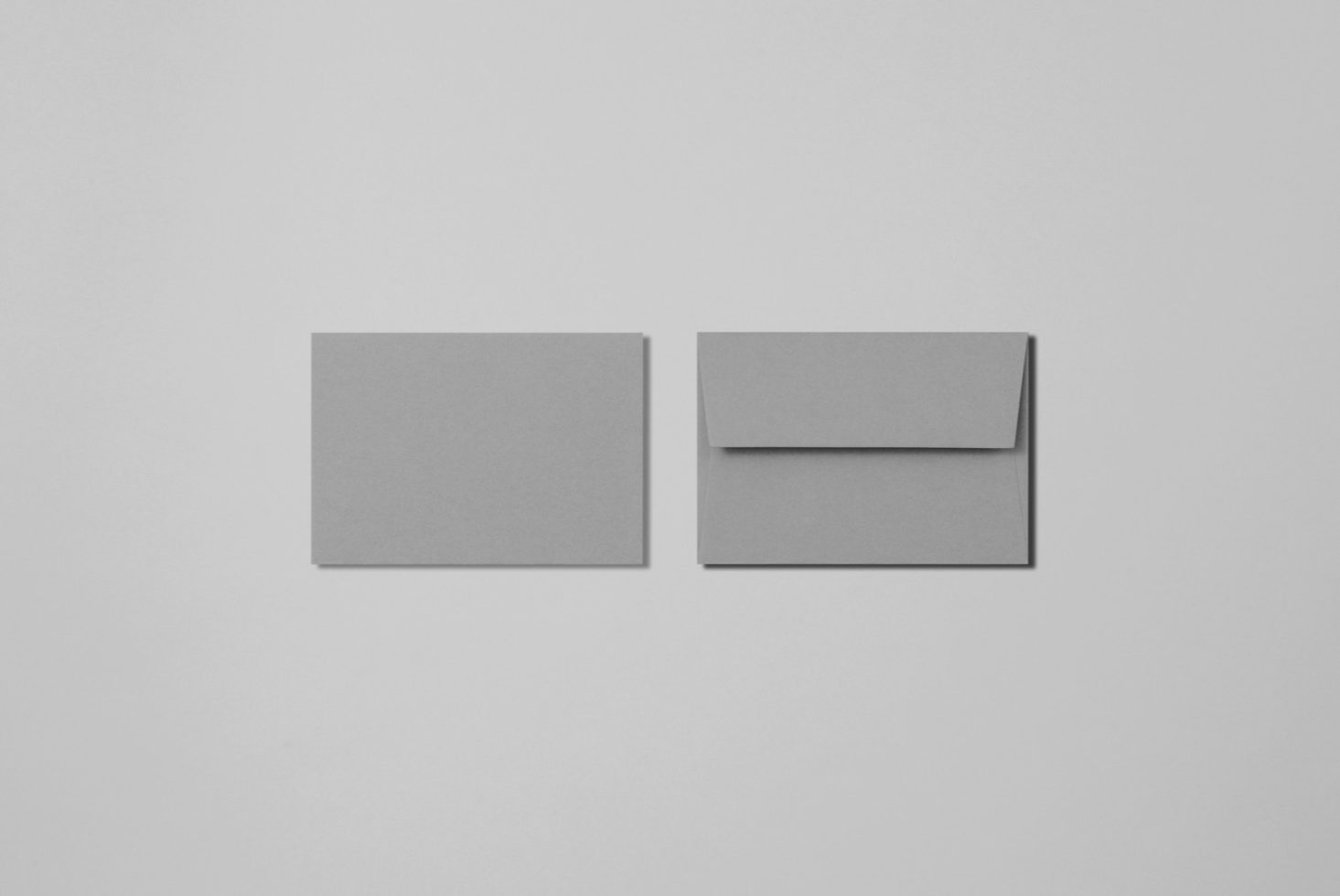 Minimalist stationery mockup featuring a plain card and envelope on a gray background, ideal for designers to showcase branding designs.