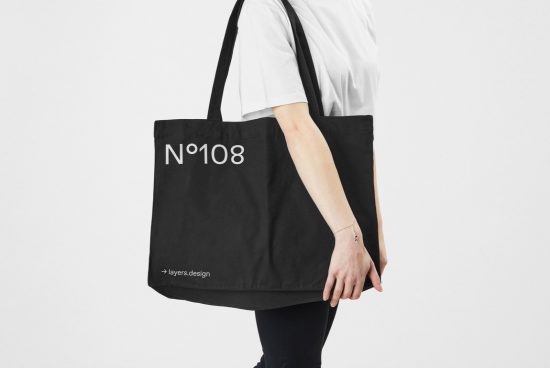 Person holding black tote bag mockup with minimalist text design, ideal for branding presentations and graphic designs.