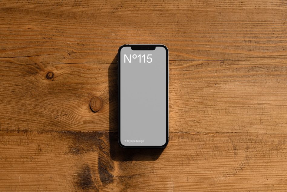 iPhone with light gray display showing N°115 on natural wood surface