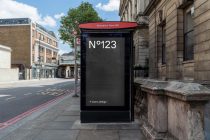 Black bus shelter with red canopy at Shoreditch Town Hall, displaying mockup space