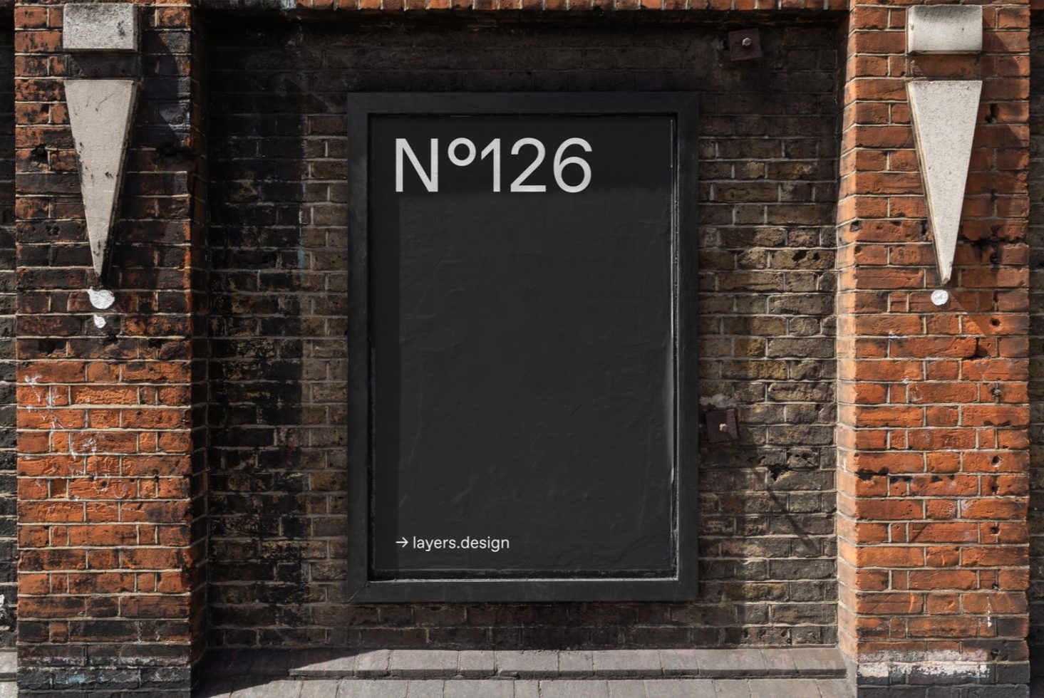 Urban poster mockup on a dark framed billboard against brick wall texture, suitable for designers to showcase work.