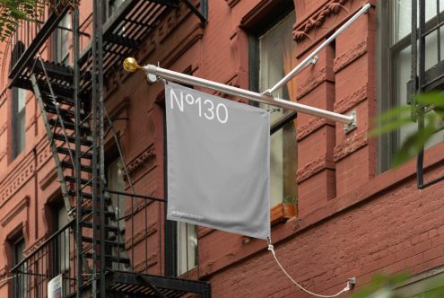 Urban flag mockup displayed outside a brick building, showcasing clear space for design templates or logos, ideal for brand identity visuals.