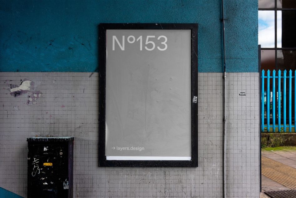 Framed poster N°153 on weathered teal wall next to blue fence