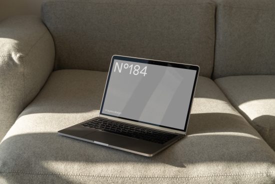 Laptop on sofa with blank screen for mockup design, natural lighting, ideal for digital asset portfolio display, professional workspace concept.