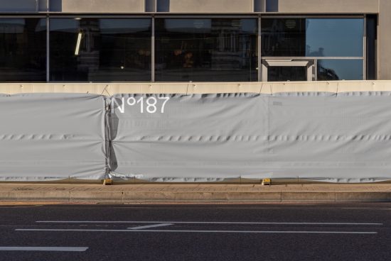 Urban building facade covered with a construction scrim featuring minimalistic design, ideal for mockup graphics or templates.
