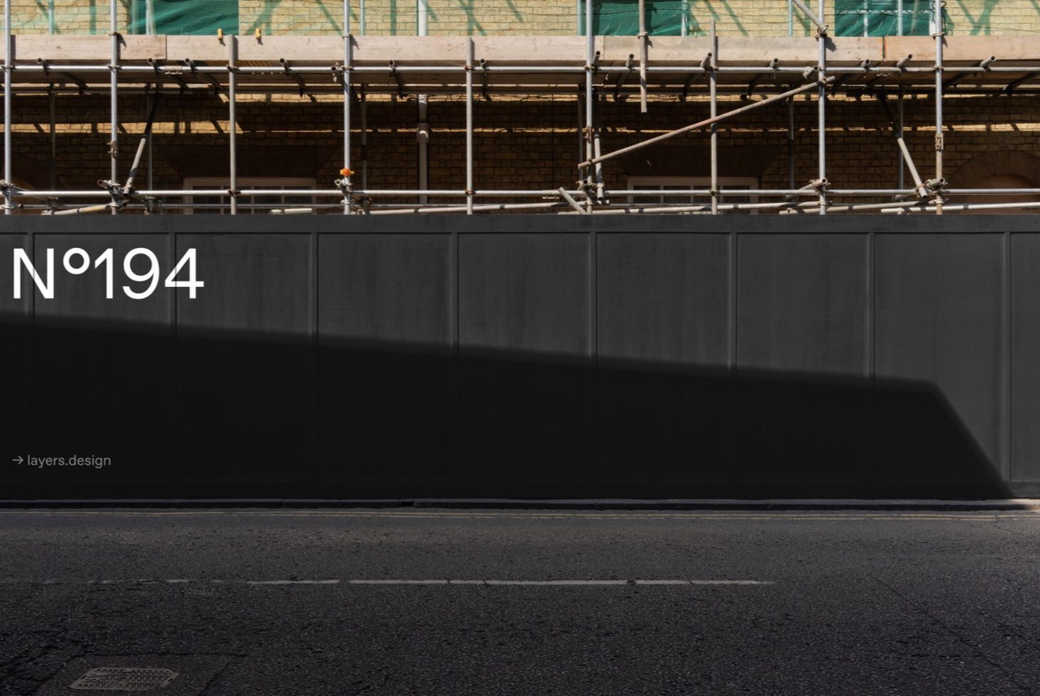 Urban construction site hoarding with scaffolding and shadow, featuring bold typography, suitable for mockup designs and templates.