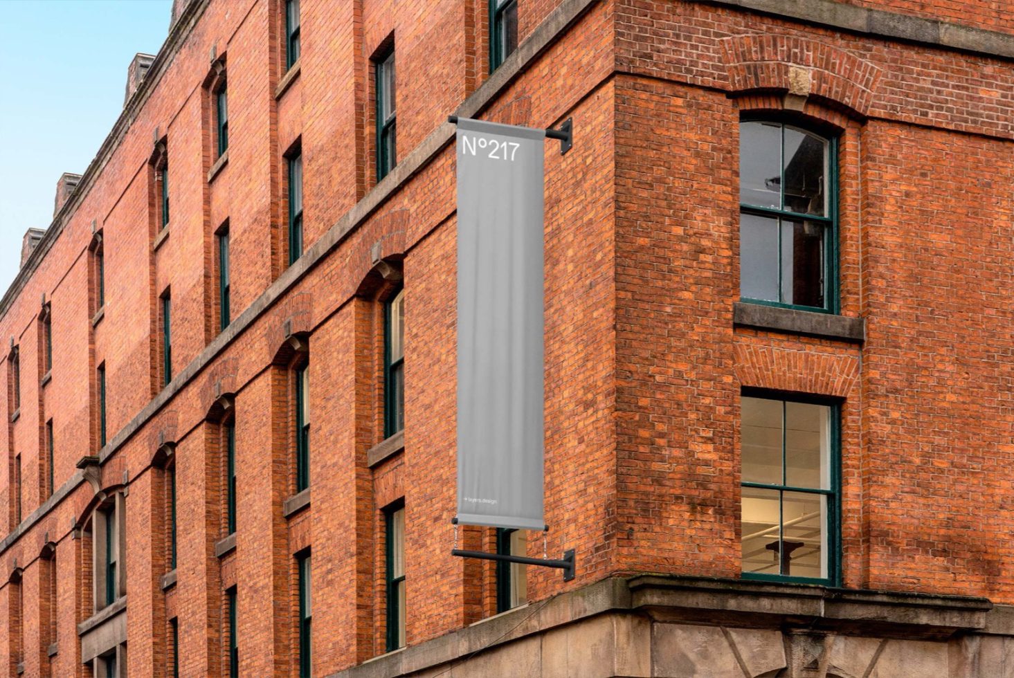 Vertical banner mockup on a building facade for outdoor advertising design presentations, brick texture visible, clear sky.