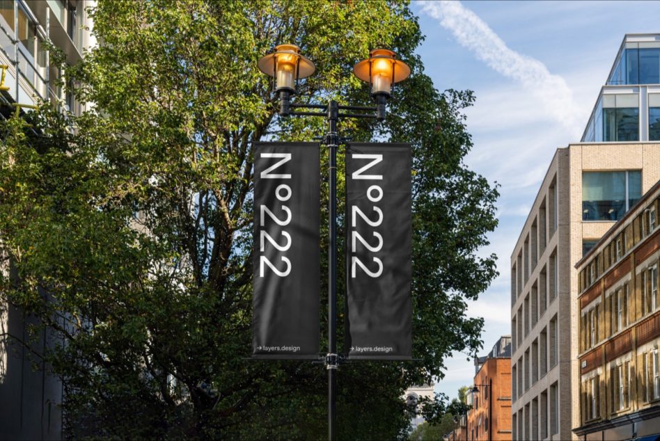 Two dark vertical street banners hanging from lamp post between buildings