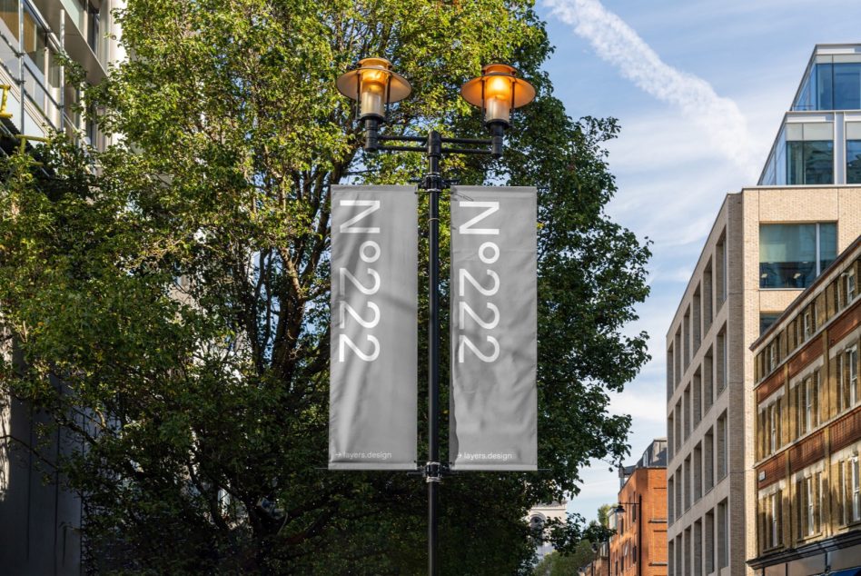 Two gray vertical street banners hanging from lamp post between buildings