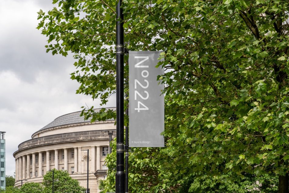 Outdoor banner mockup on light pole with classical building backdrop, urban setting, designer assets, realistic graphic template.