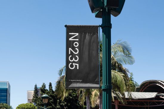 Street banner mockup hanging on a lamp post with palm trees and blue sky in the background, ideal for urban design presentations.