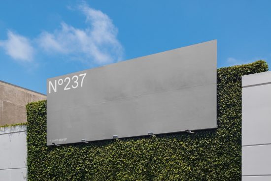 Billboard mockup on a building with ivy and clear blue sky, editable design for advertising, urban outdoor signage.