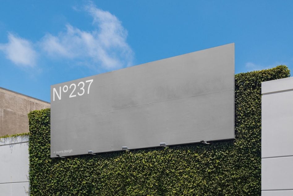 Minimalist billboard N°237 flanked by lush green ivy walls, bright daylight