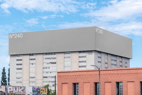 Urban billboard mockup on building facade with clear sky for advertising design presentation, photo-realistic cityscape, editable template.