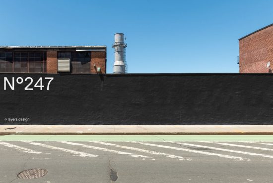 Urban street wall mockup with large black space for design display, clear blue sky and brick building backdrop for graphic assets.